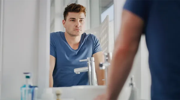 Ein Mann betrachtet sich im Spiegel